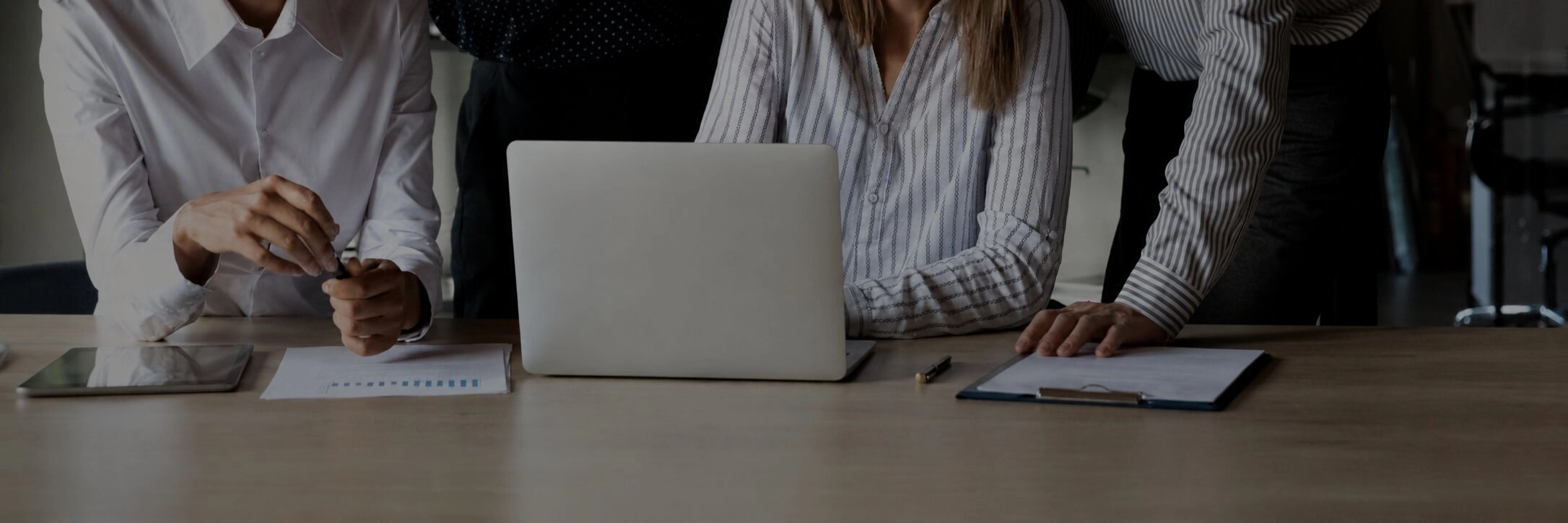 Team of professionals collaborating around a laptop in a modern office